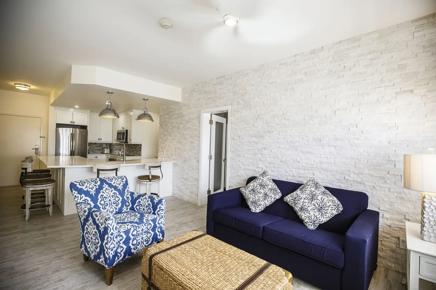 Suite living area with blue sofa, patterned chair, and kitchen beyond at Ports of Call Resort.