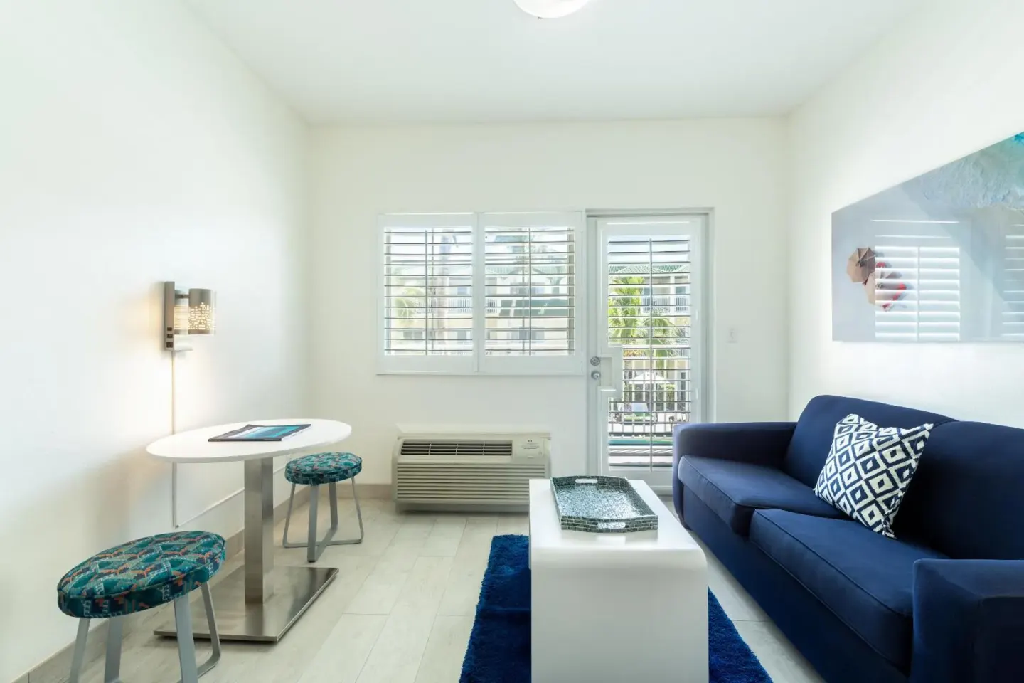 Guest room sitting area with blue sofa, small table, and balcony door at Ports of Call Resort.