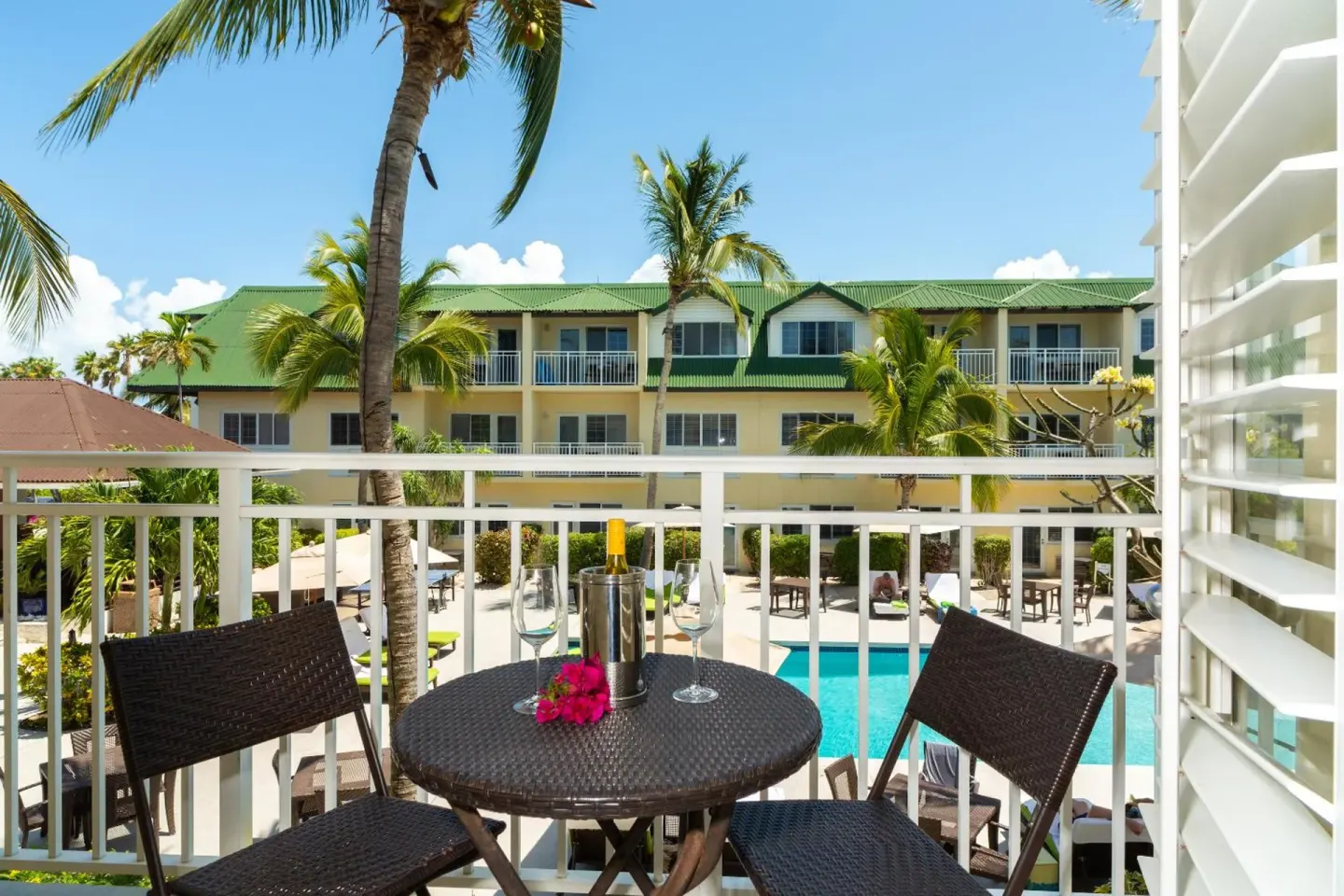 Pool-view balcony with table, chairs, and glasses at Ports of Call Resort.