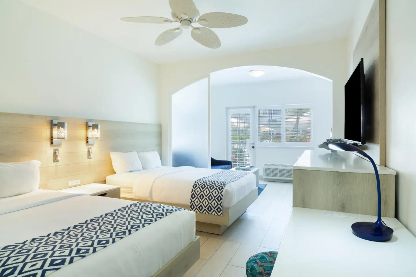 Two-bed guest room with desk and TV at Ports of Call Resort.