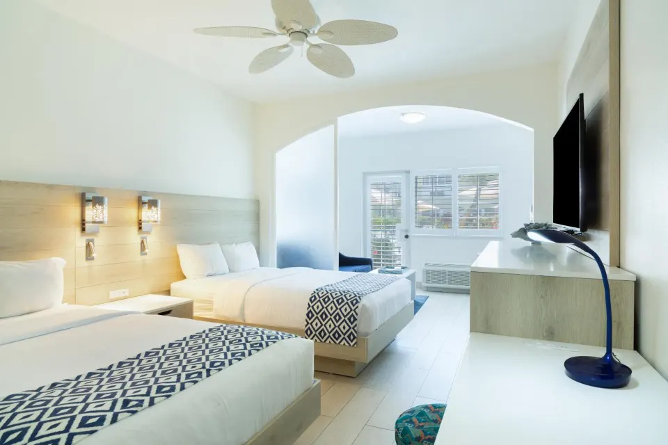 Two-bed guest room with desk and TV at Ports of Call Resort.