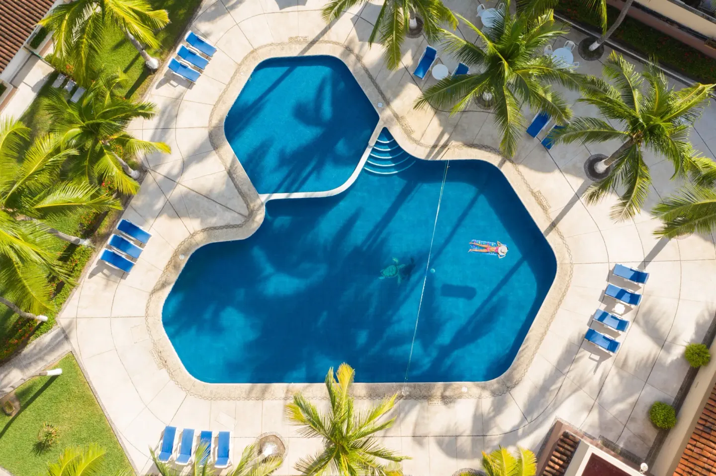An overhead view of the palm-lined pool deck at Posada Real Ixtapa.