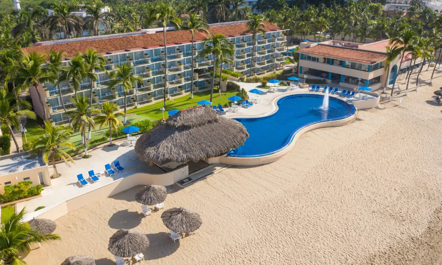Aerial view of the beachfront pool, palapas and resort buildings at Posada Real Ixtapa.
