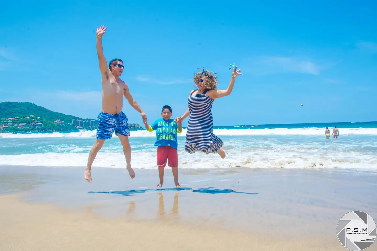A family jumps on the shoreline in front of the waves at Posada Real Ixtapa.