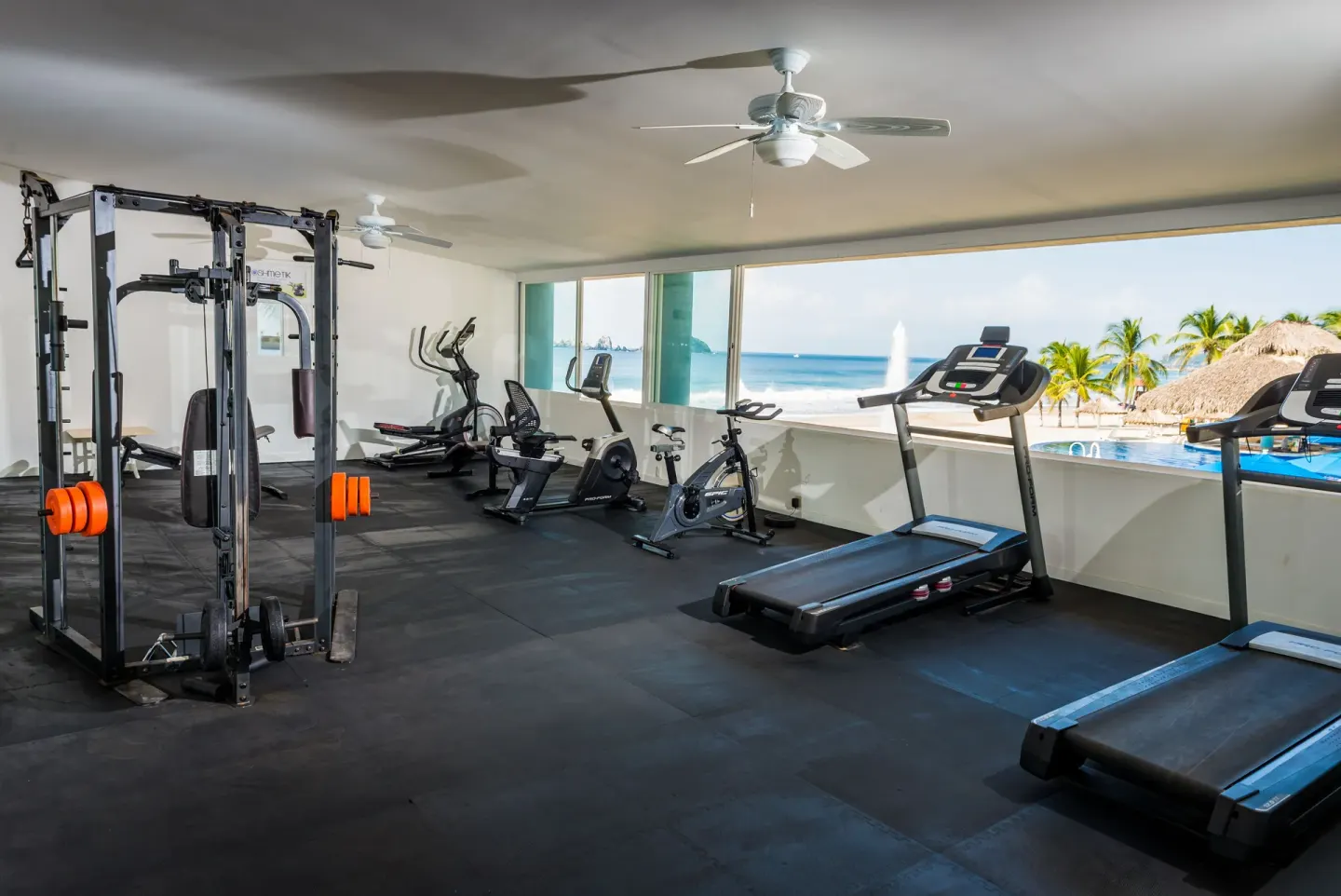 Fitness room with treadmills, bikes and ocean-facing windows at Posada Real Ixtapa.