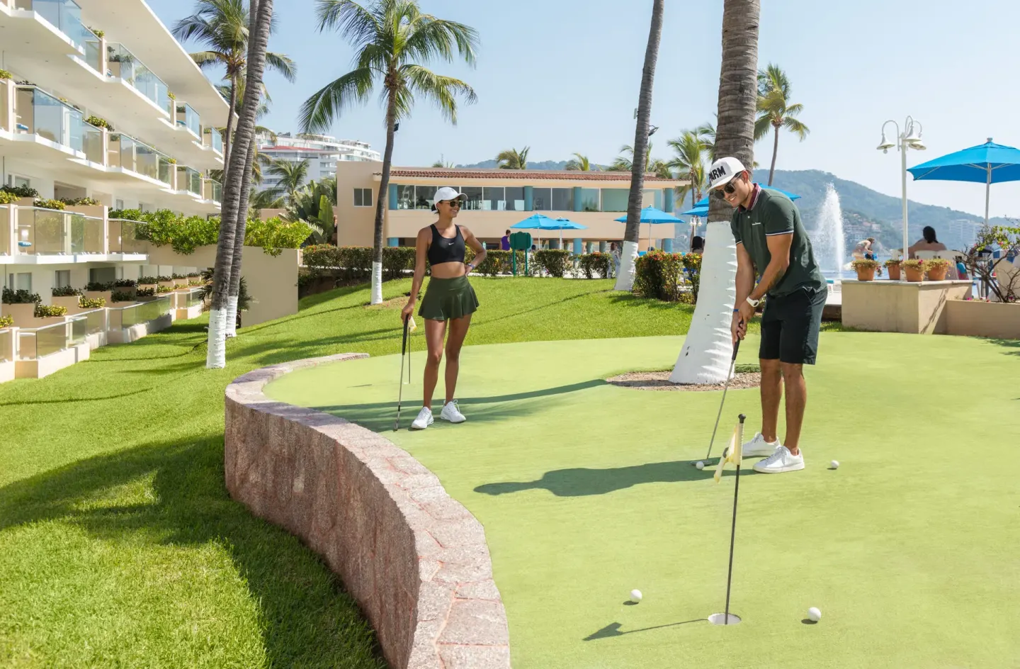 Guests play mini golf on a green lawn near the pool at Posada Real Ixtapa.