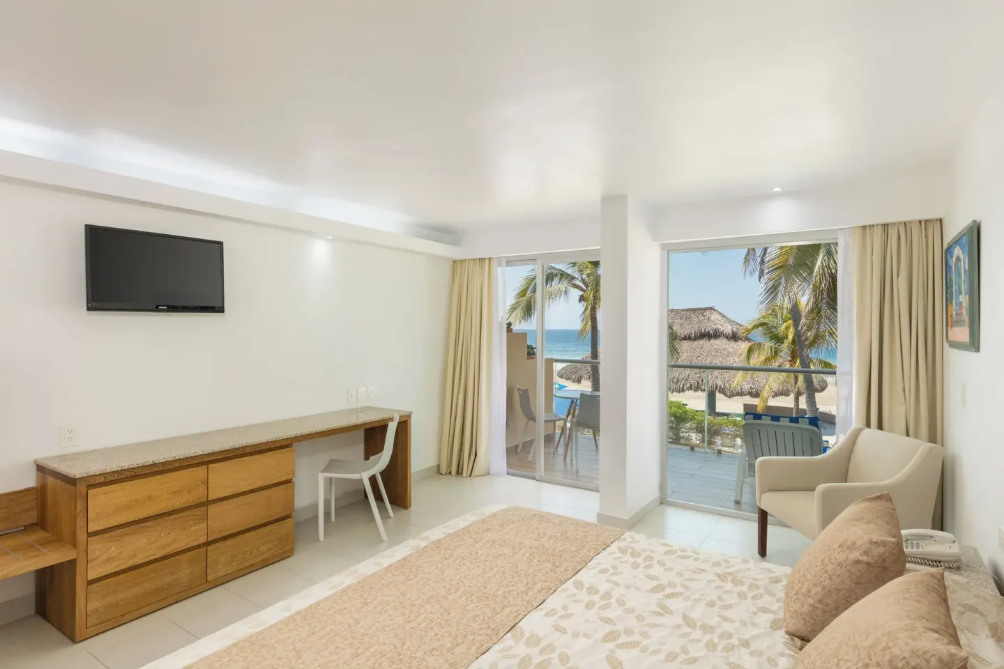 Guest room with one bed, seating, desk, balcony, and ocean view at Posada Real Ixtapa.