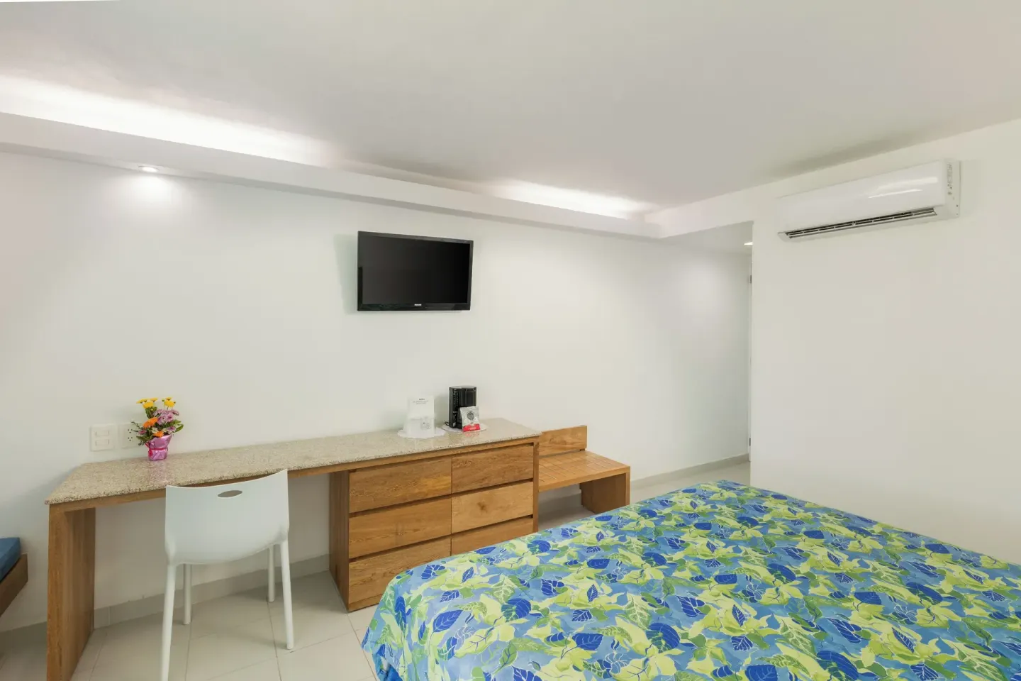 Guest room with one bed, desk, dresser, TV, and air conditioner at Posada Real Ixtapa.