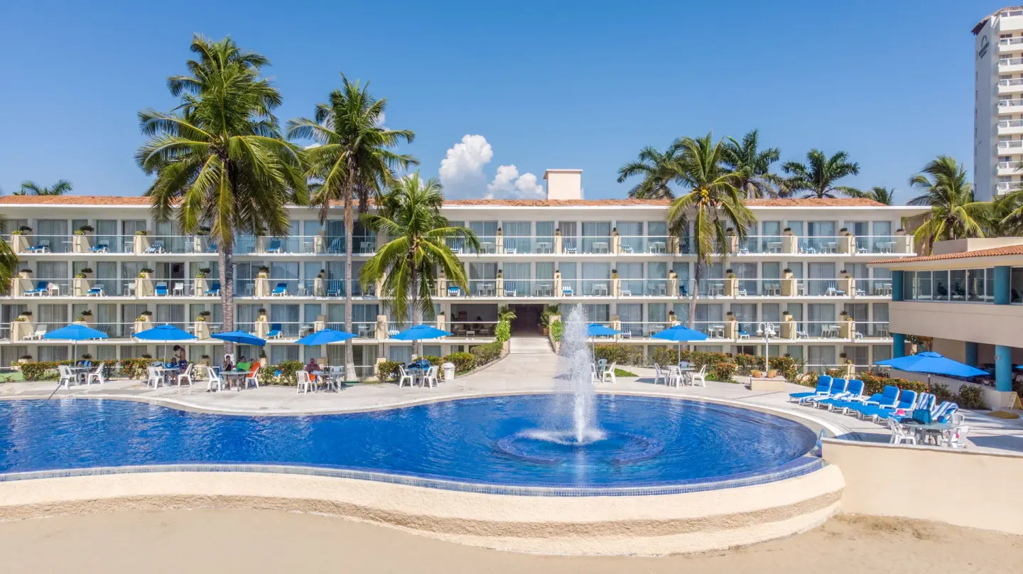 The main pool with a fountain and guest room balconies at Posada Real Ixtapa.