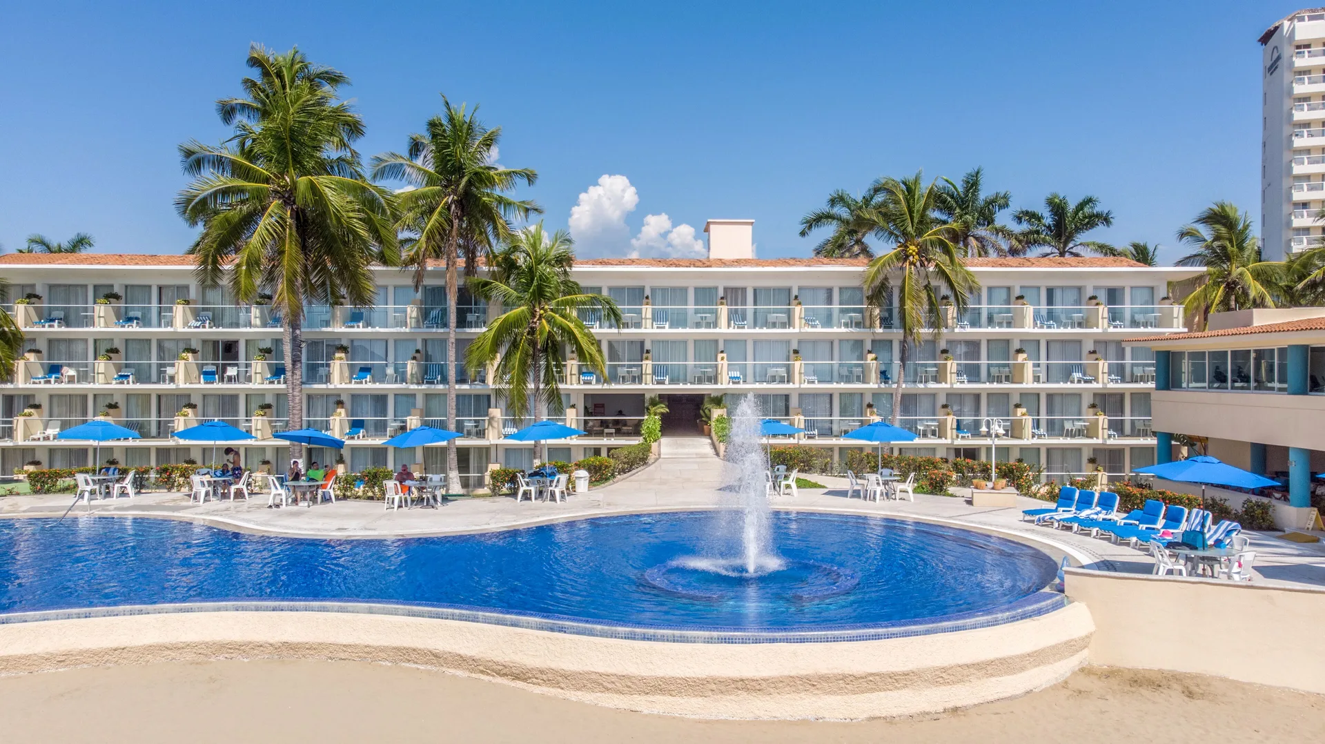 The main pool with a fountain and guest room balconies at Posada Real Ixtapa.