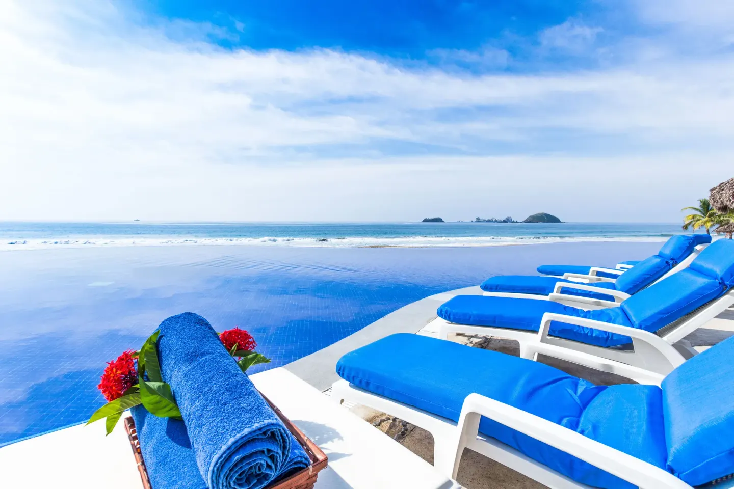 Blue pool loungers overlook the ocean at Posada Real Ixtapa.