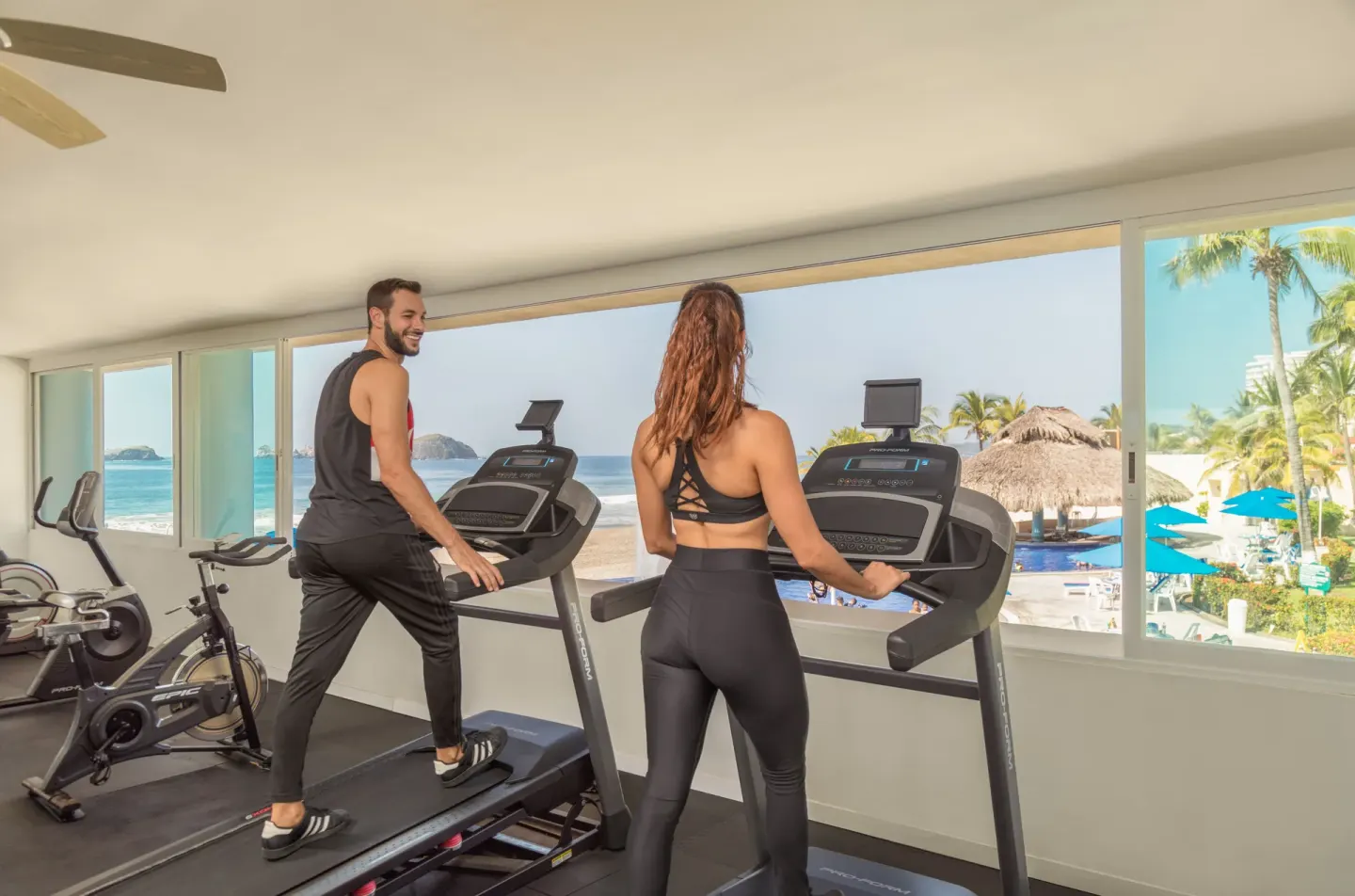 Guests using treadmills in an ocean-view fitness room at Posada Real Ixtapa.