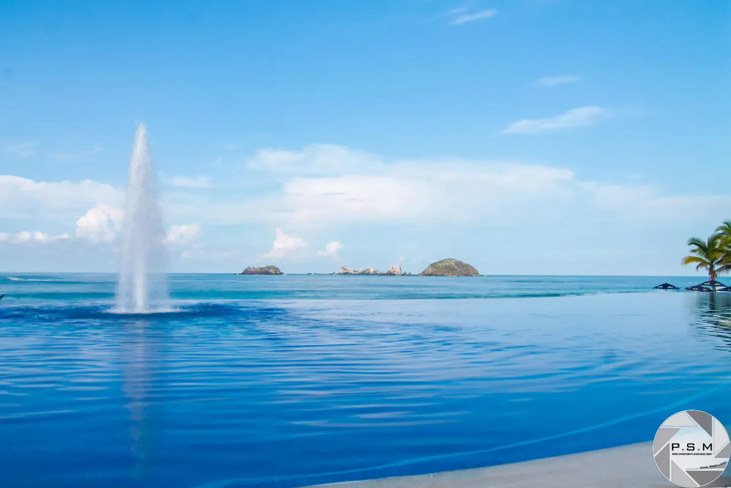 Pool fountain with ocean and small islands beyond at Posada Real Ixtapa.