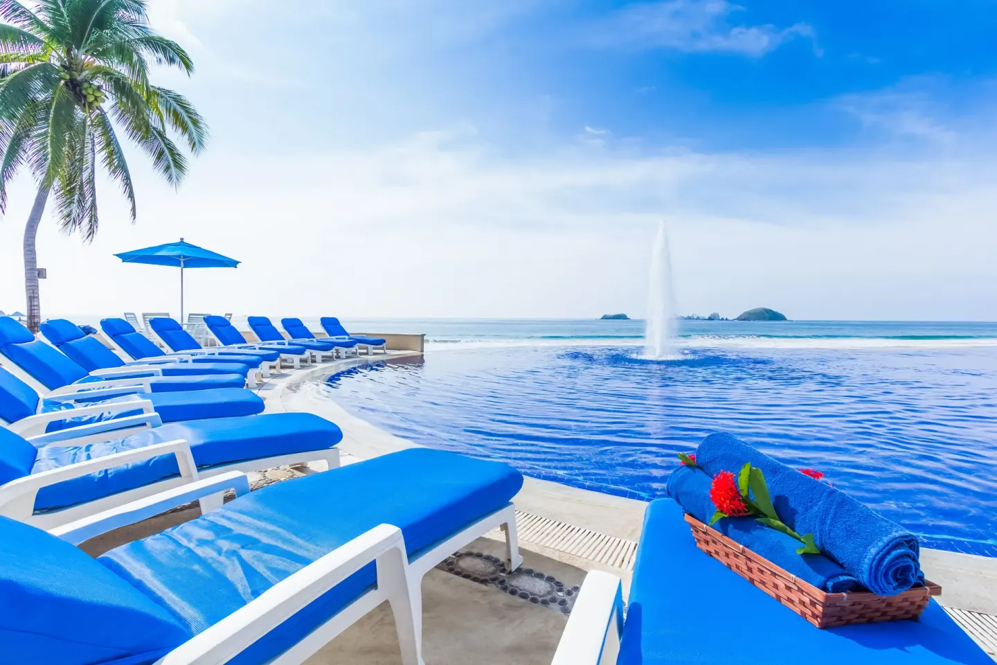 Poolside loungers, towels, flowers, and ocean views at Posada Real Ixtapa.
