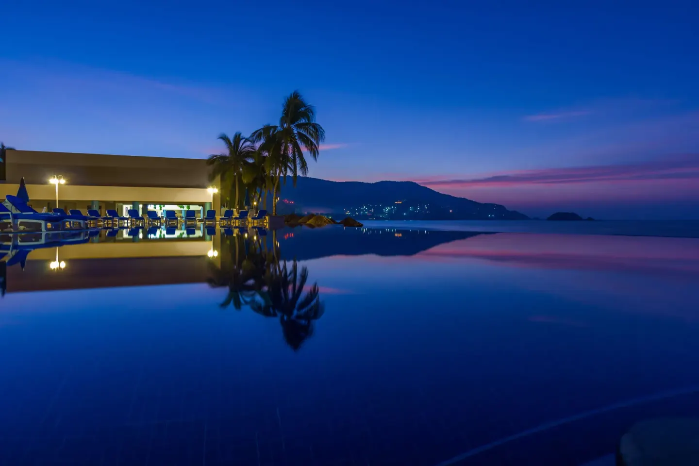 Infinity-style pool reflecting palms and sunset colors at Posada Real Ixtapa.