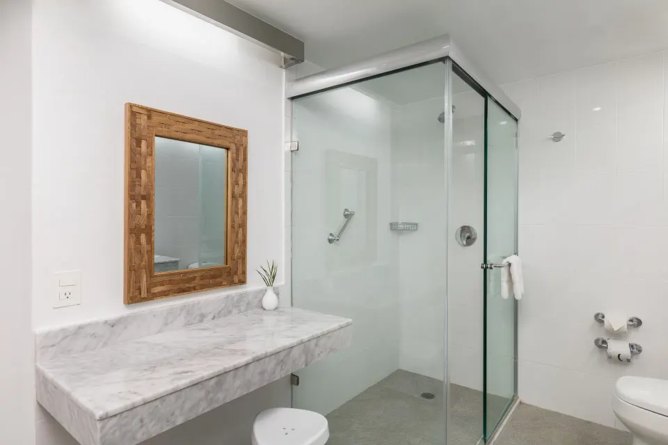Superior Room bathroom with marble-look vanity and glass shower at Posada Real Ixtapa.