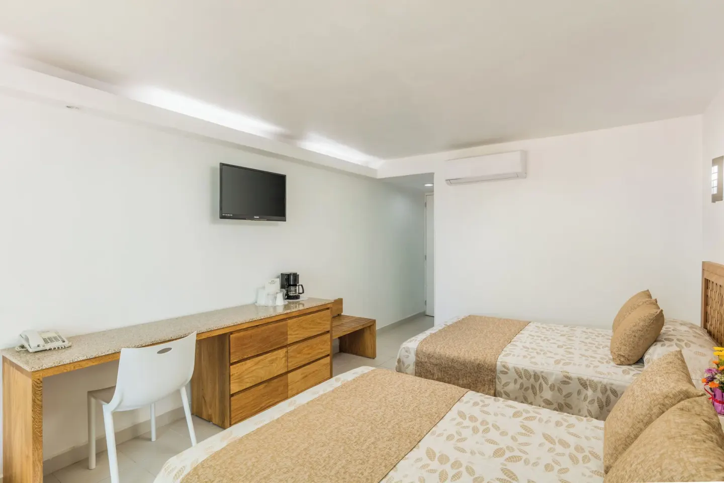Superior Room with two beds, desk, dresser and wall TV at Posada Real Ixtapa.