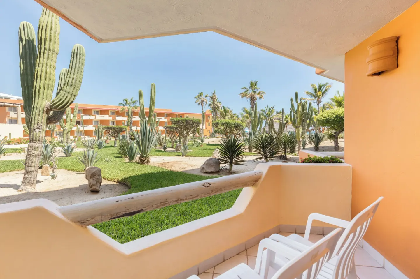 Balcony seating overlooks cactus gardens and orange buildings at Posada Real Los Cabos.
