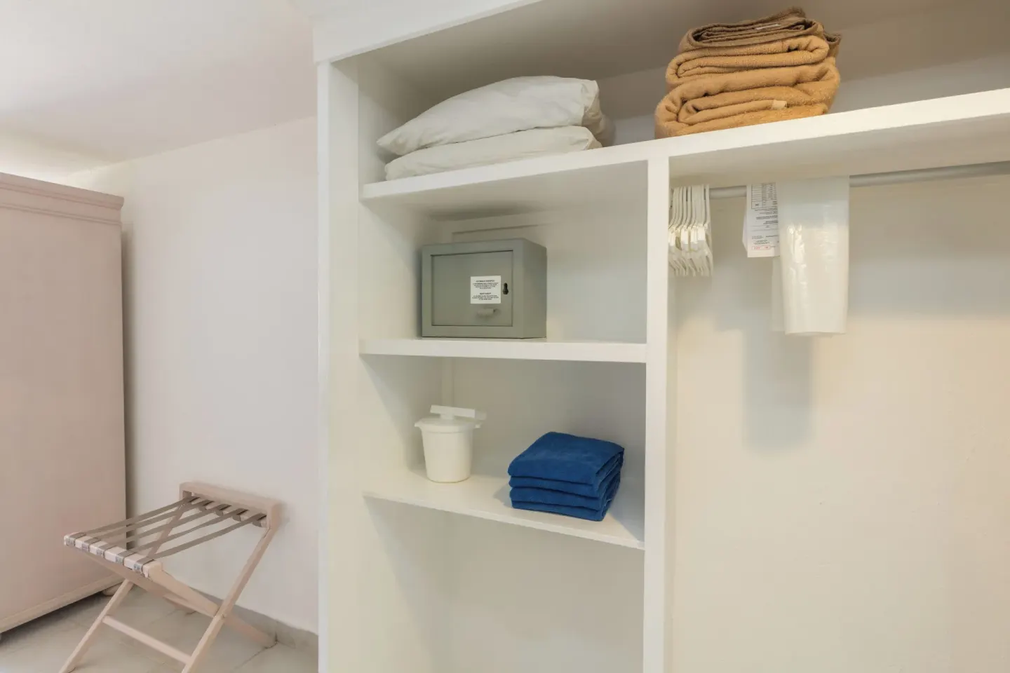Guest room closet shelves with safe, towels, hangers, and luggage rack at Posada Real Los Cabos.