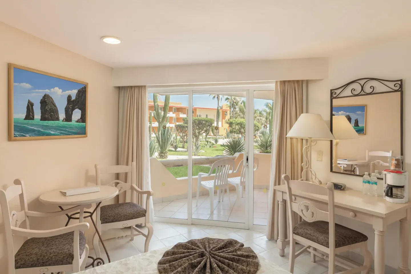 Guest room sitting area with patio doors and garden view at Posada Real Los Cabos.