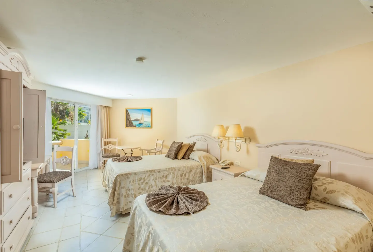 Guest room with two double beds, balcony doors and white furniture at Posada Real Los Cabos.