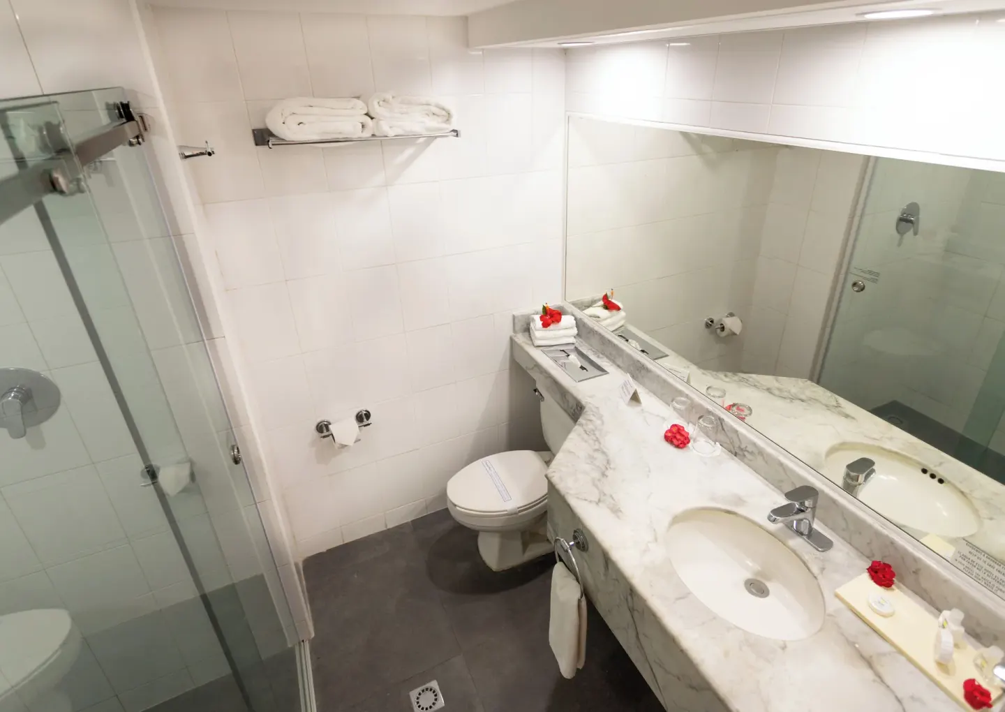 Bright bathroom with shower, towels, mirror, and vanity in a standard room at Posada Real Los Cabos.