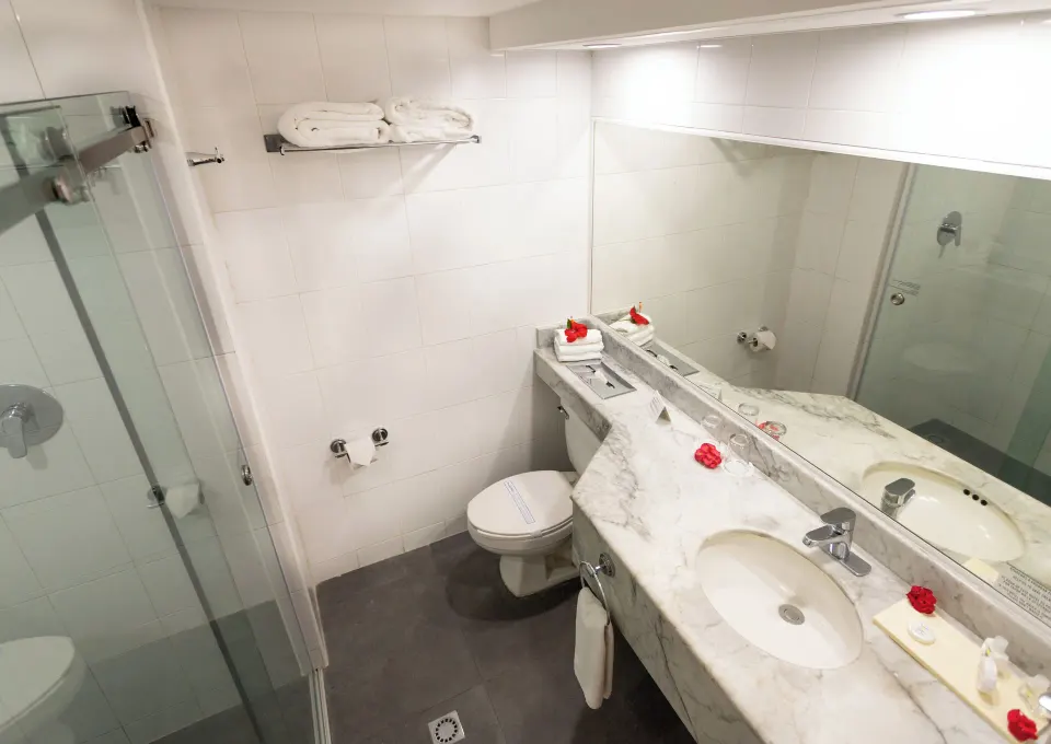 Bright bathroom with shower, towels, mirror, and vanity in a standard room at Posada Real Los Cabos.