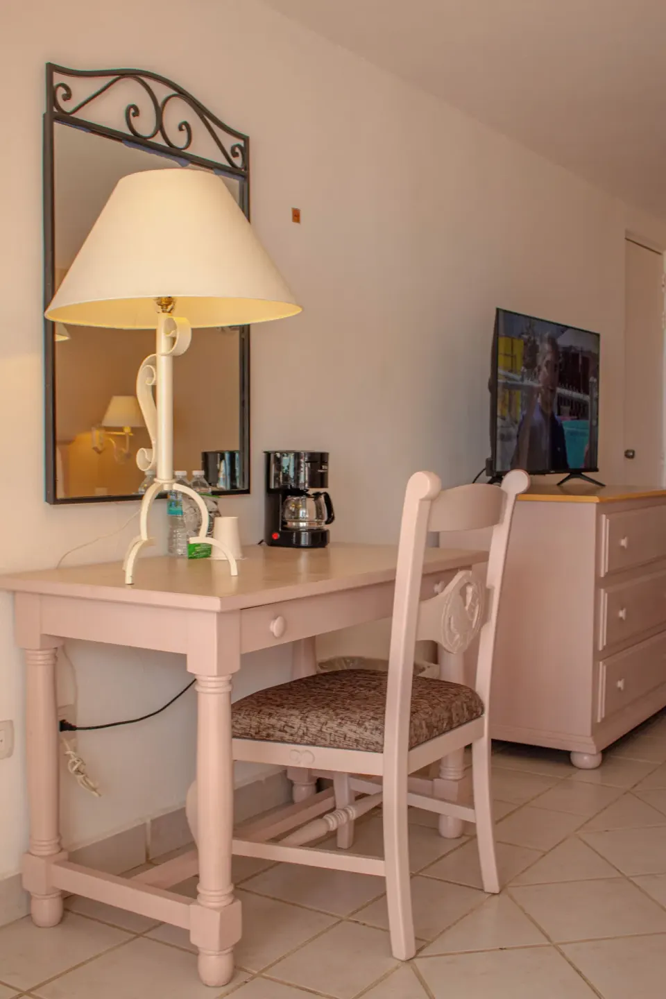 Desk area with mirror, coffee maker, chair, dresser, and TV at Posada Real Los Cabos.