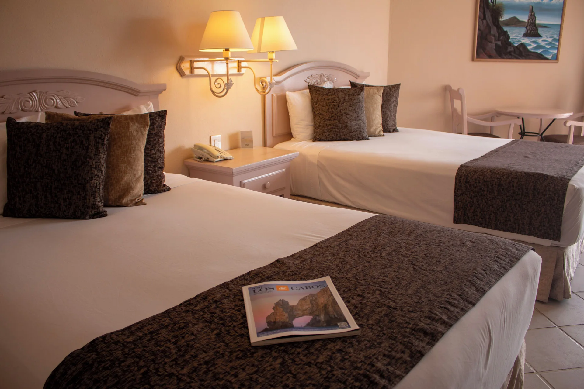 Two made beds with patterned runners and bedside lamps at Posada Real Los Cabos.