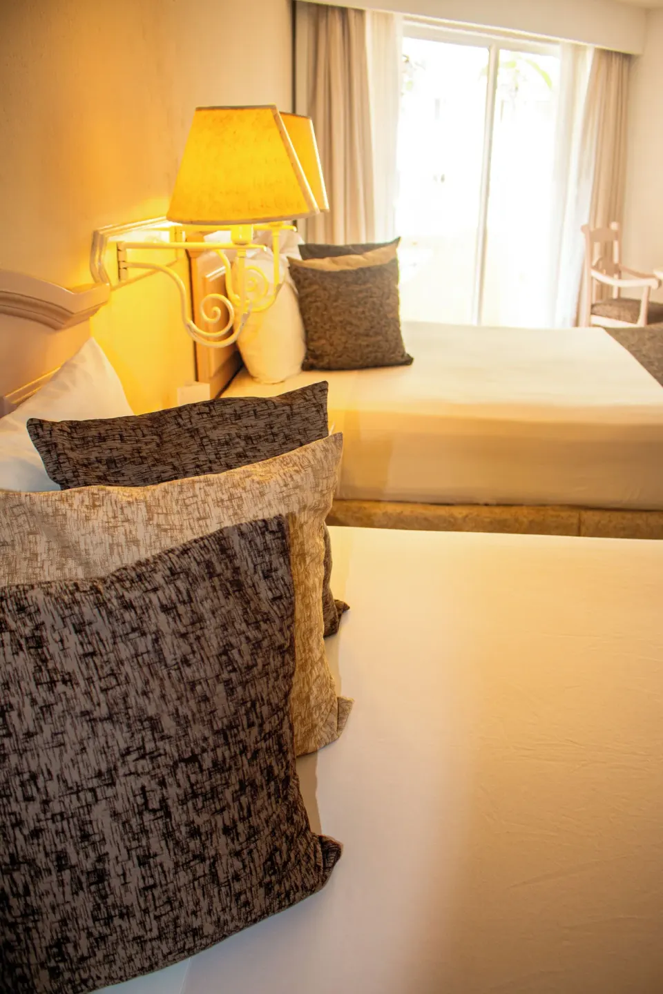 Two beds with patterned pillows in a standard room at Posada Real Los Cabos.