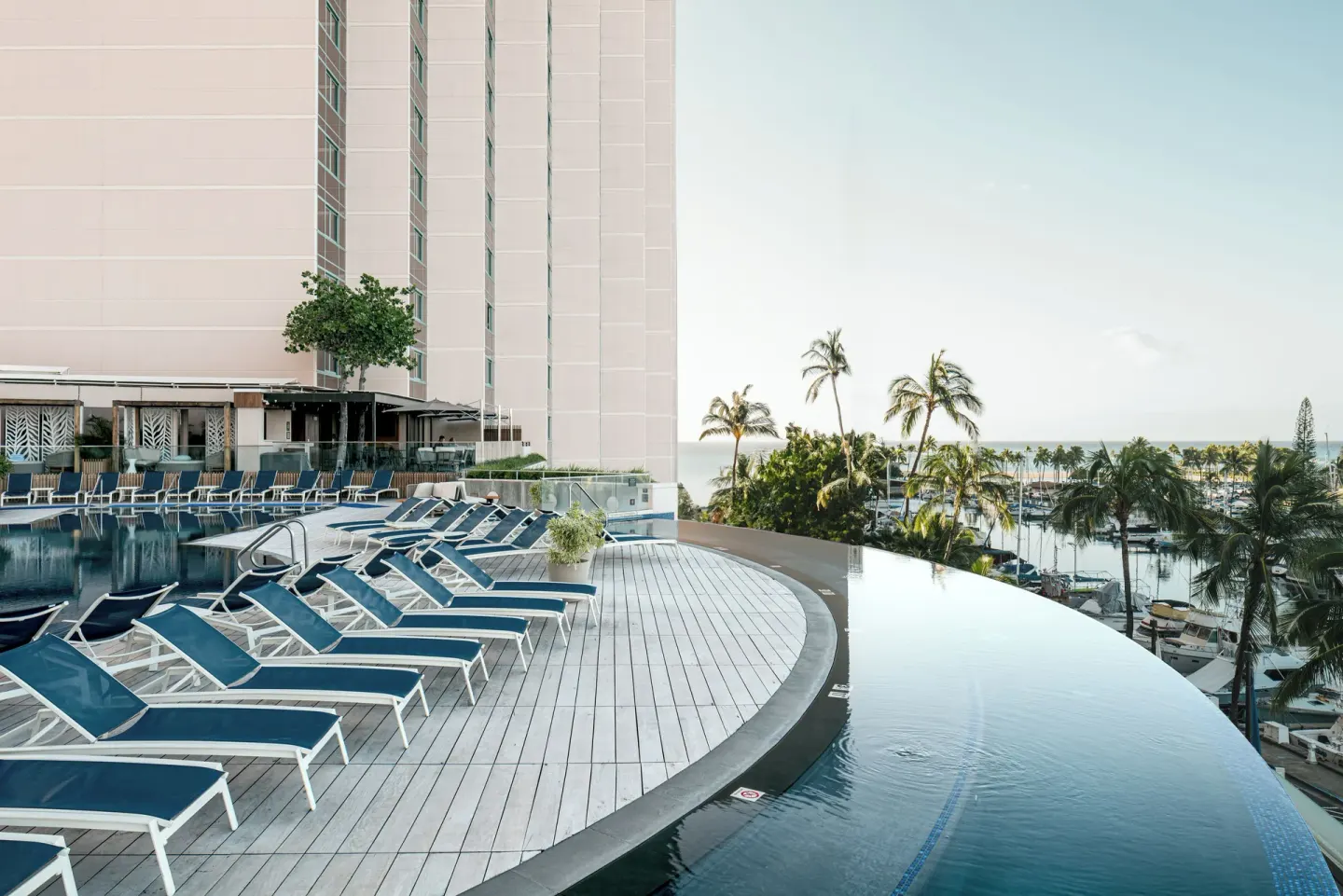 Infinity pool deck with lounge chairs overlooking the marina at Prince Waikiki.