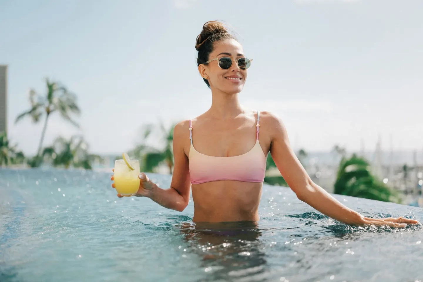 Guest holding a tropical drink in the infinity pool at Prince Waikiki.