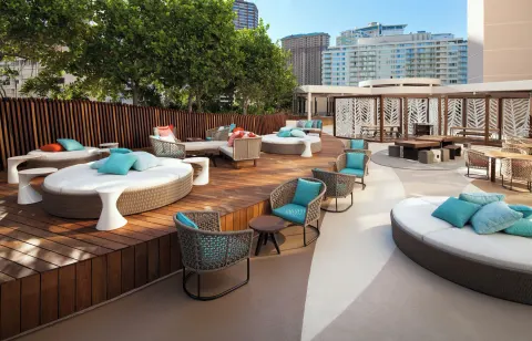 Outdoor lounge deck with round daybeds and turquoise pillows at Prince Waikiki.