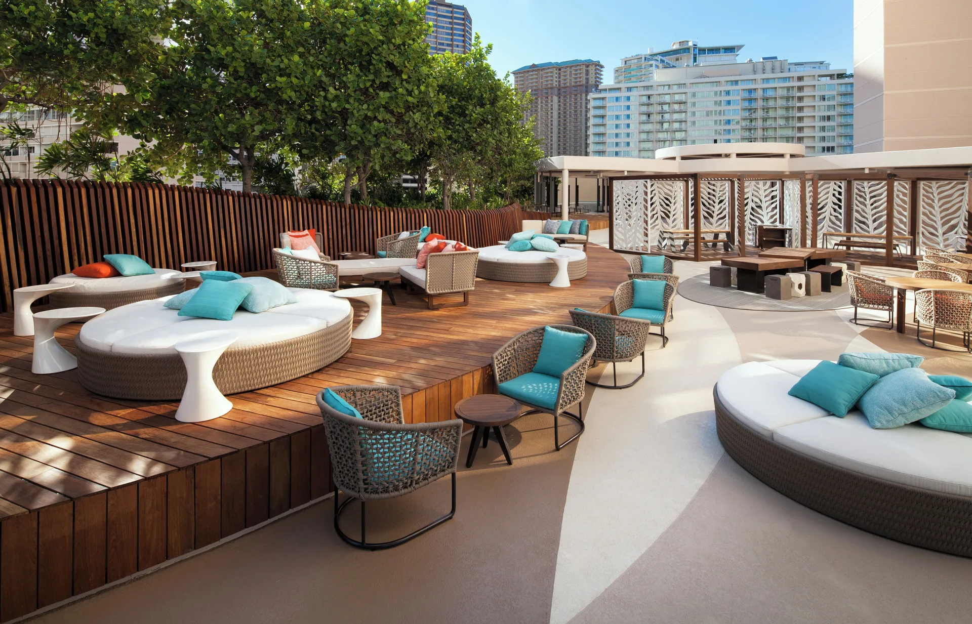 Outdoor lounge deck with round daybeds and turquoise pillows at Prince Waikiki.