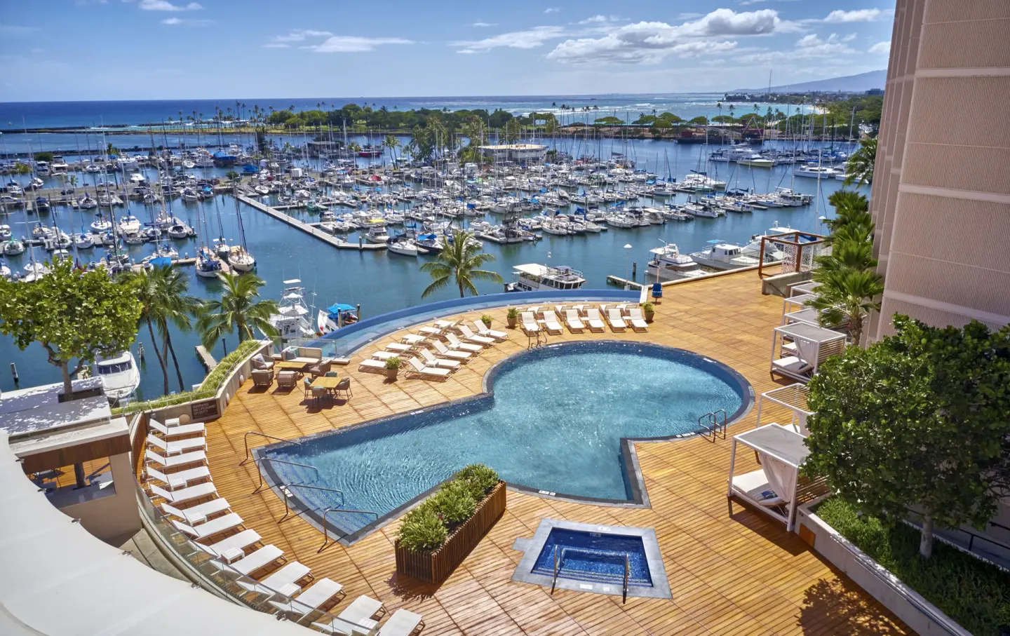 Prince Waikiki pool deck with loungers, cabanas, marina, and ocean views.