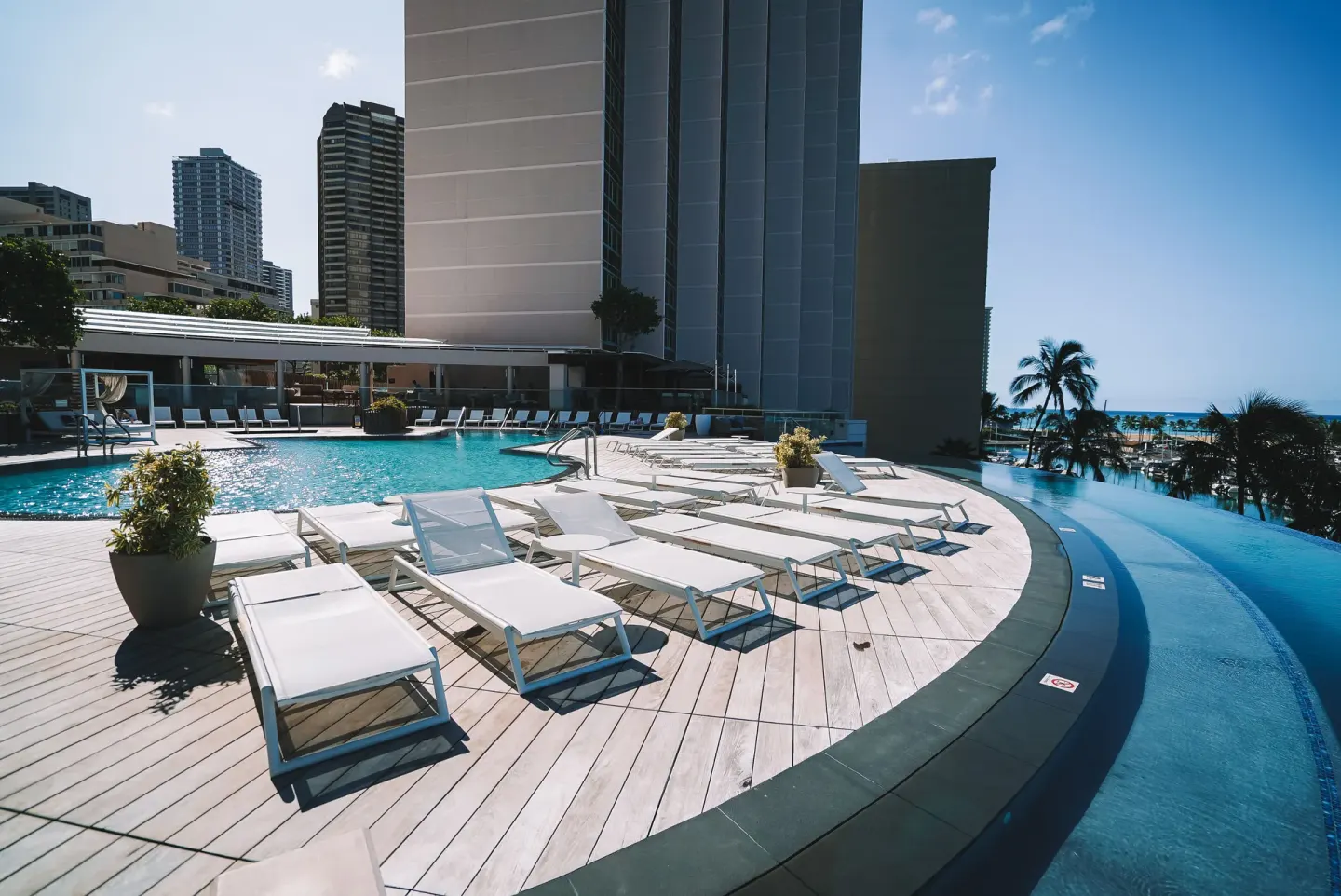 Sun loungers beside the pool and curved water edge at Prince Waikiki.