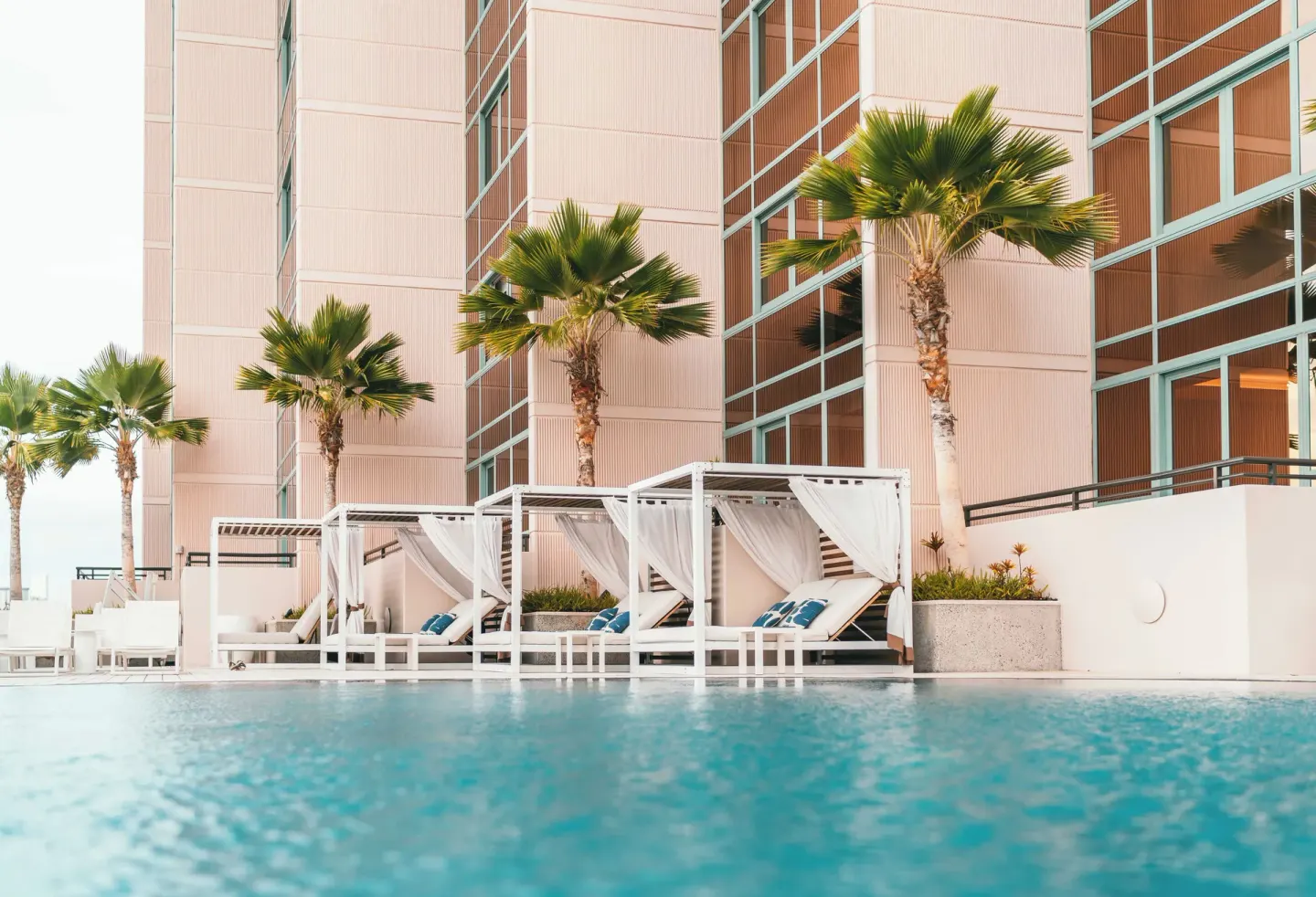 Poolside cabanas and palm trees beside the water at Prince Waikiki.