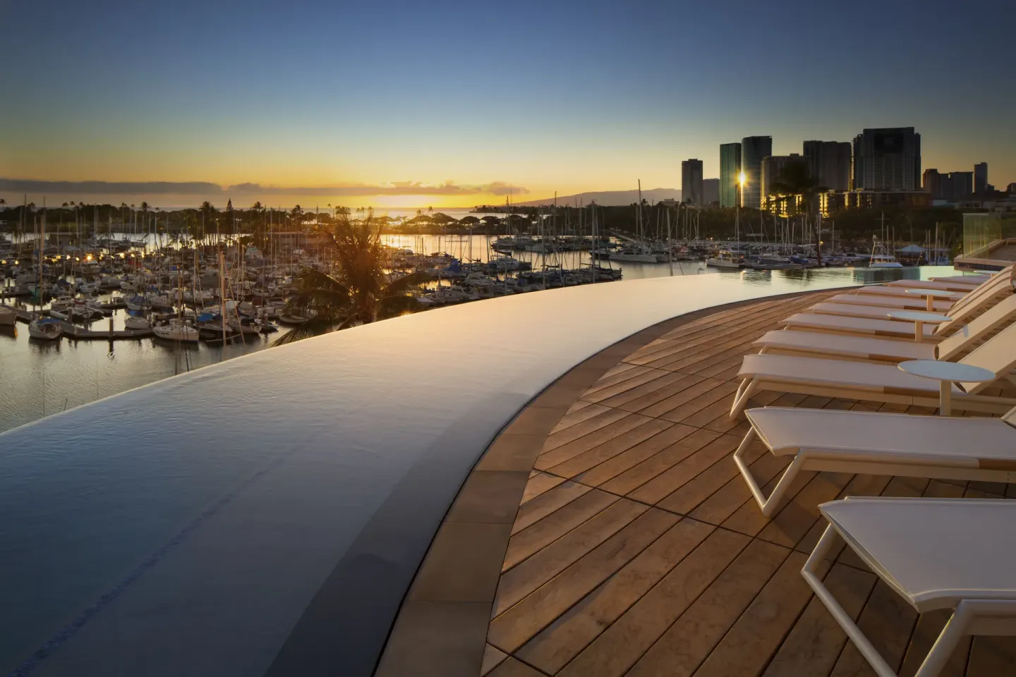Sunset over the infinity pool, marina, and city skyline at Prince Waikiki.