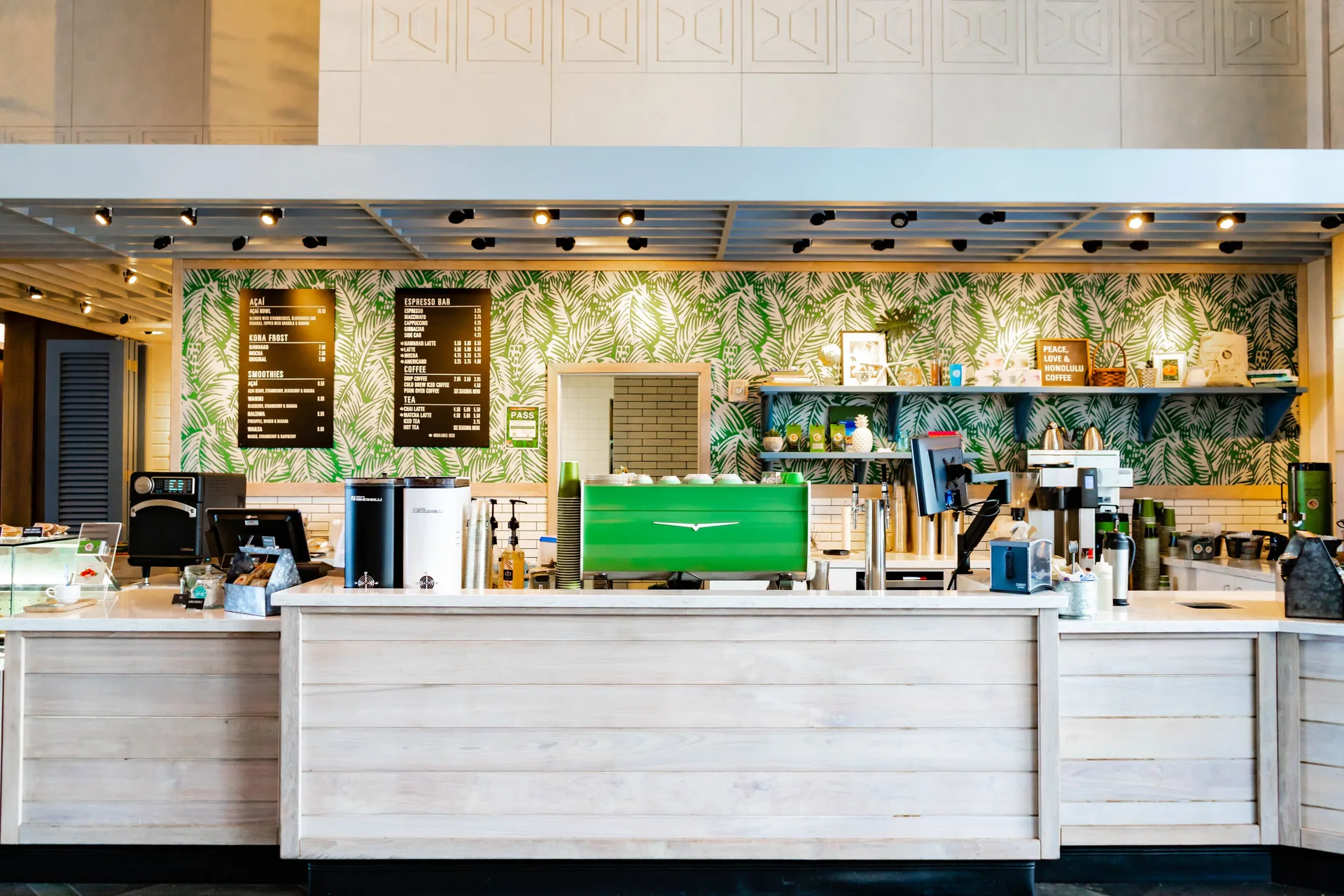 Coffee counter with tropical wall covering and menu boards at Prince Waikiki.