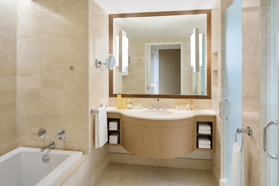 Ocean Front 1 Bedroom Suite bathroom with soaking tub, vanity, and glass shower at Prince Waikiki.