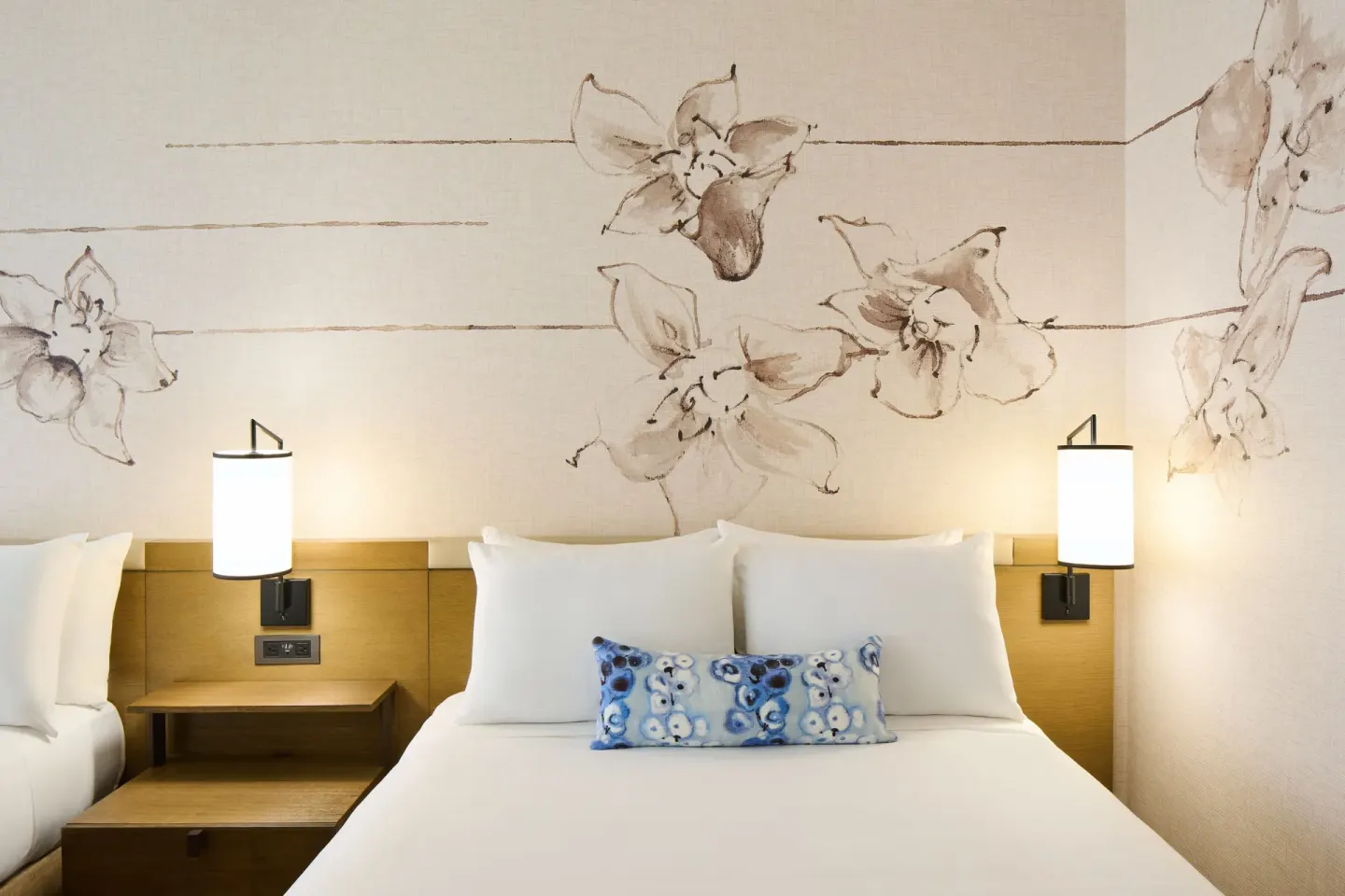 Ocean Front 1 Bedroom Suite bed with floral wall art and sconces at Prince Waikiki.