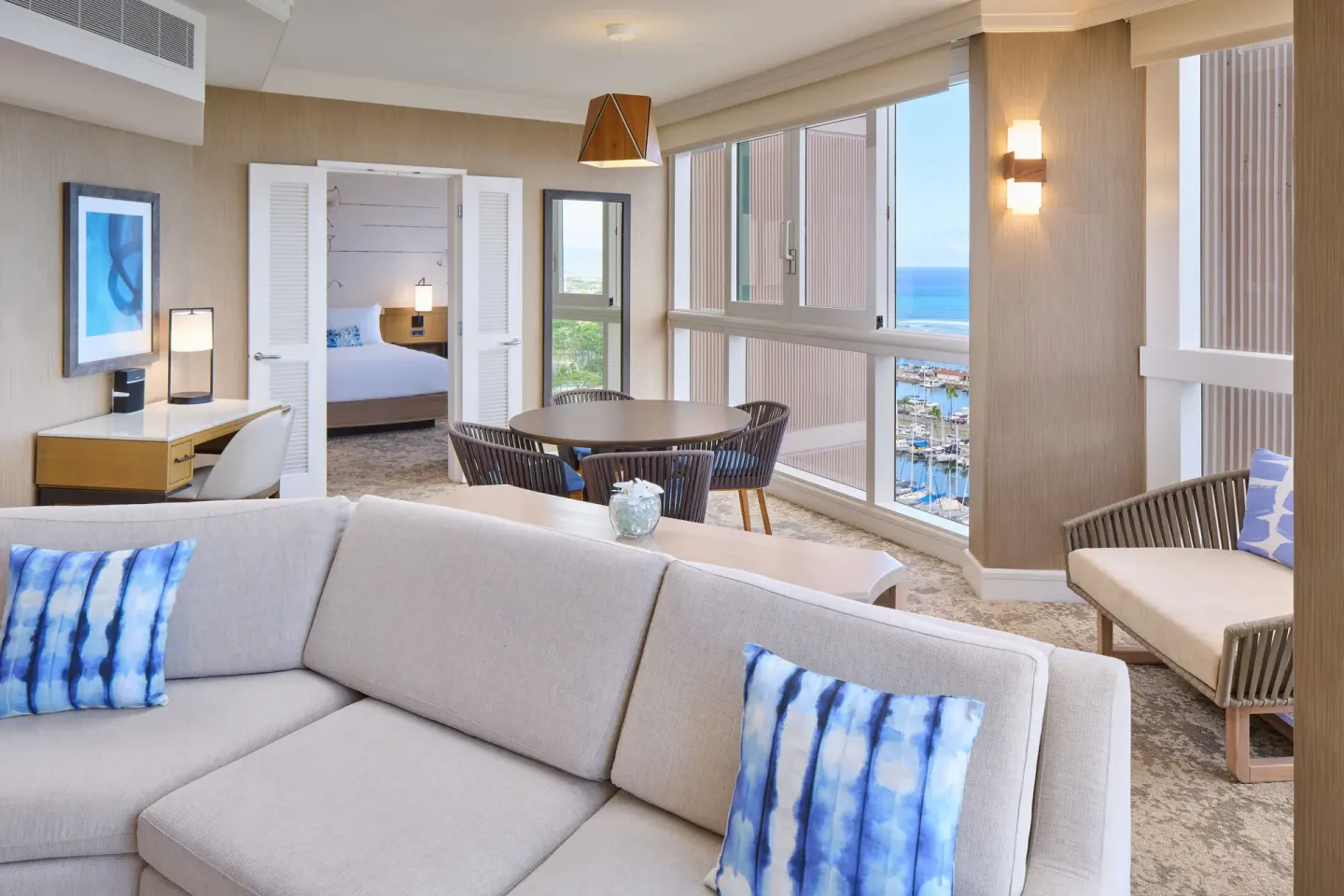 Ocean Front 1 Bedroom Suite living room with sofa, dining table, and bedroom doorway at Prince Waikiki.