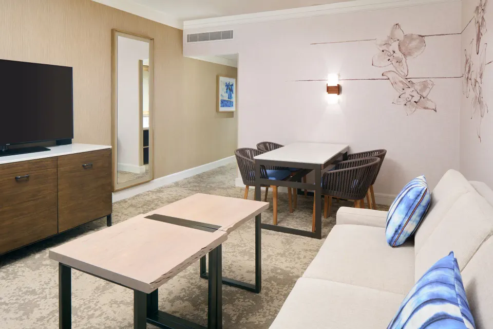 Ocean View Suite living area with sofa and dining table at Prince Waikiki.