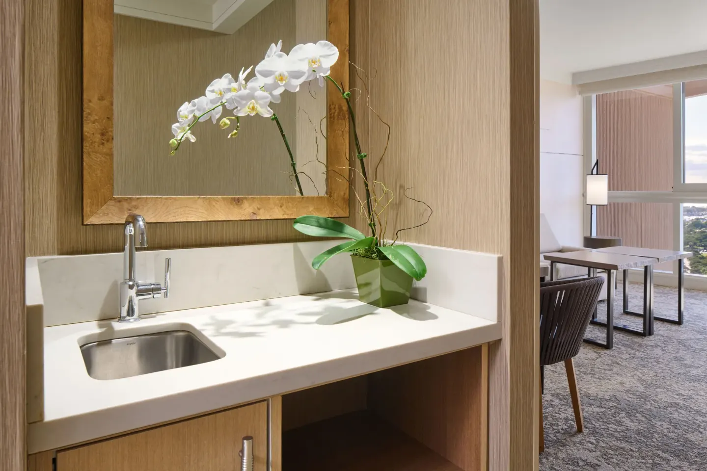 Ocean View Suite wet bar with orchid and living area beyond at Prince Waikiki.