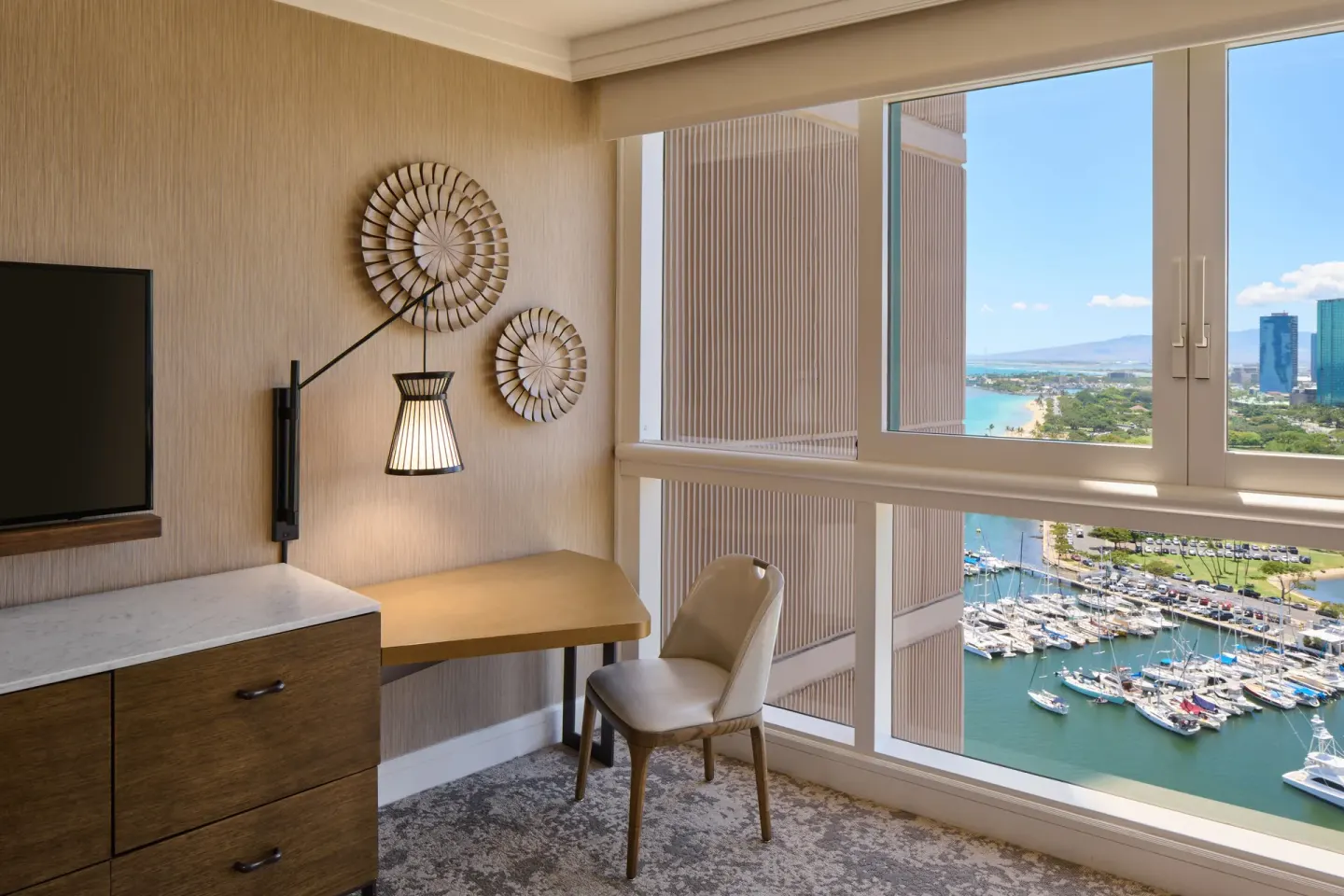 Ocean View room desk beside windows overlooking marina and skyline at Prince Waikiki.
