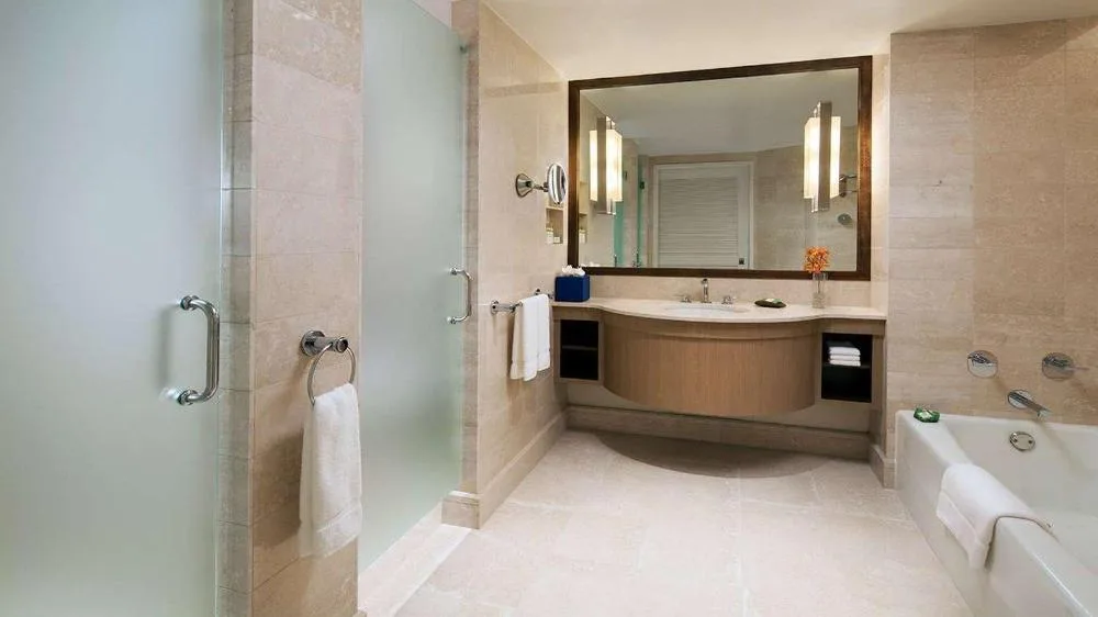 Ocean View guest room bathroom with glass shower, vanity, and soaking tub at Prince Waikiki.
