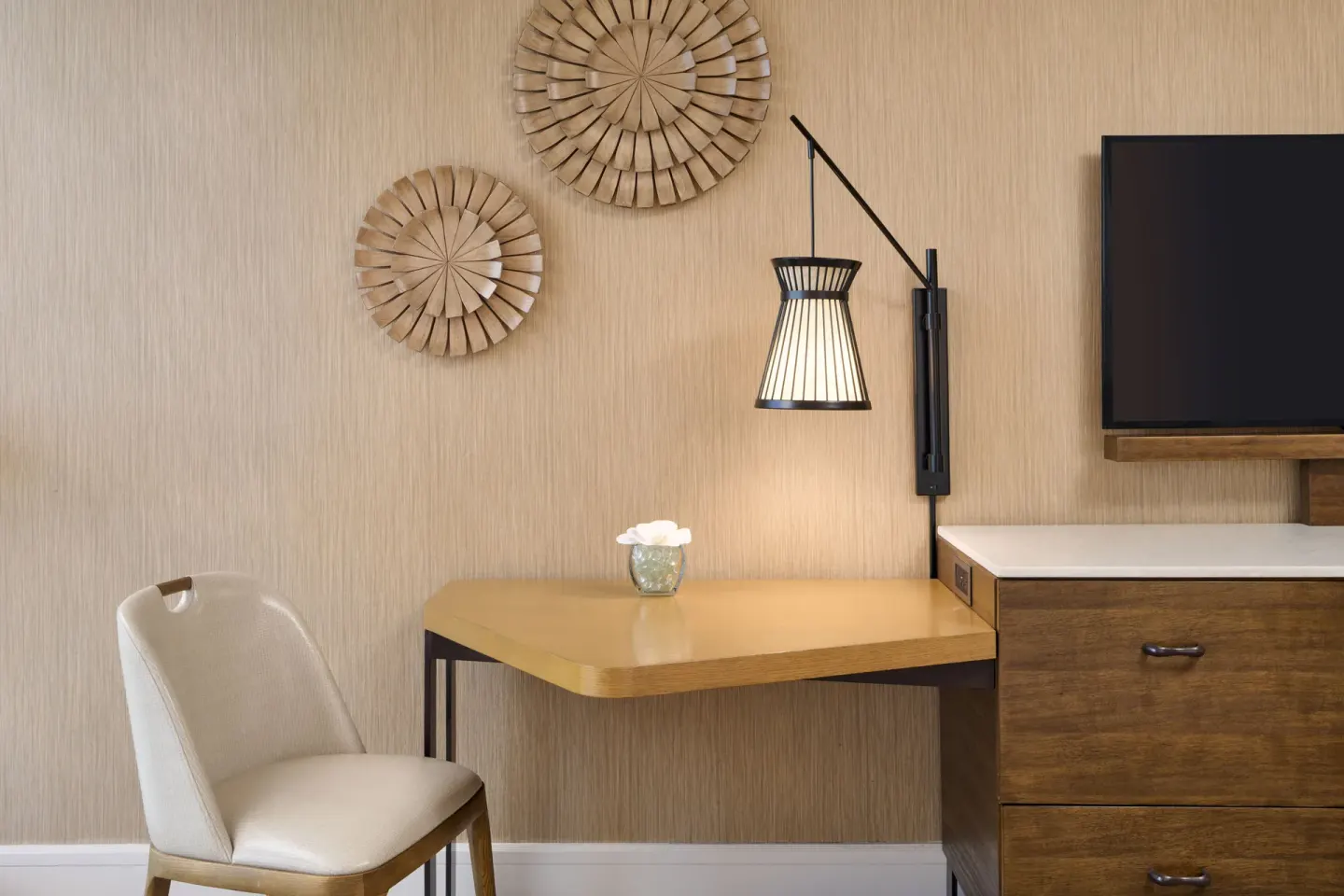 Ocean View room writing desk with chair, wall lamp, decor, and dresser at Prince Waikiki.