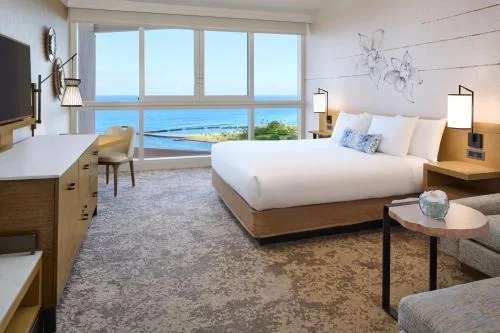 Premier Oceanfront Room king bed, work desk, and blue ocean view at Prince Waikiki.
