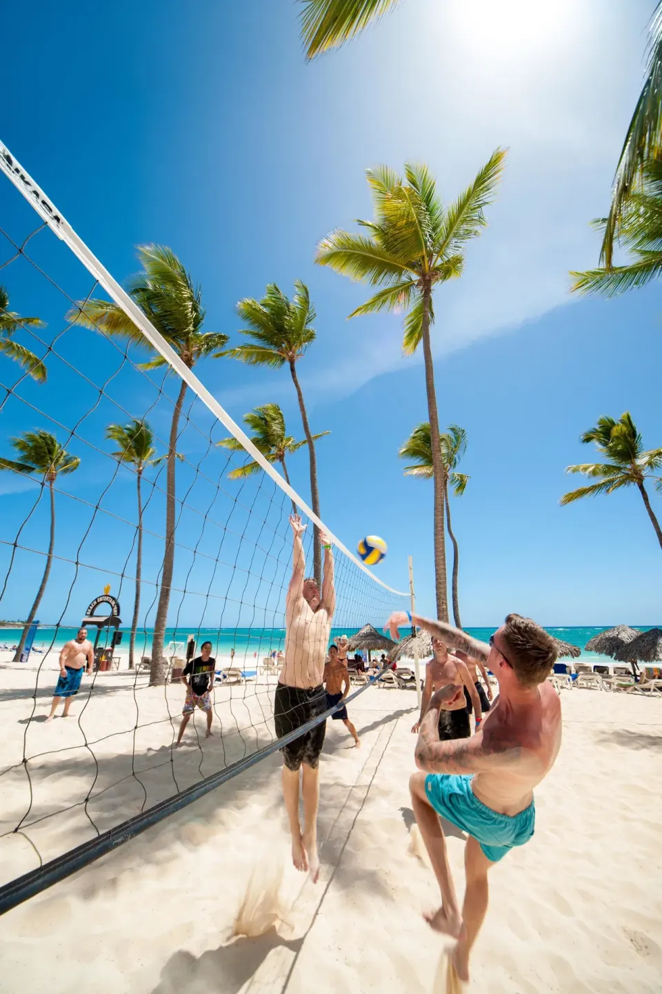 Beach volleyball game on the sand at Princess Family Club Bavaro with palms and turquoise water.