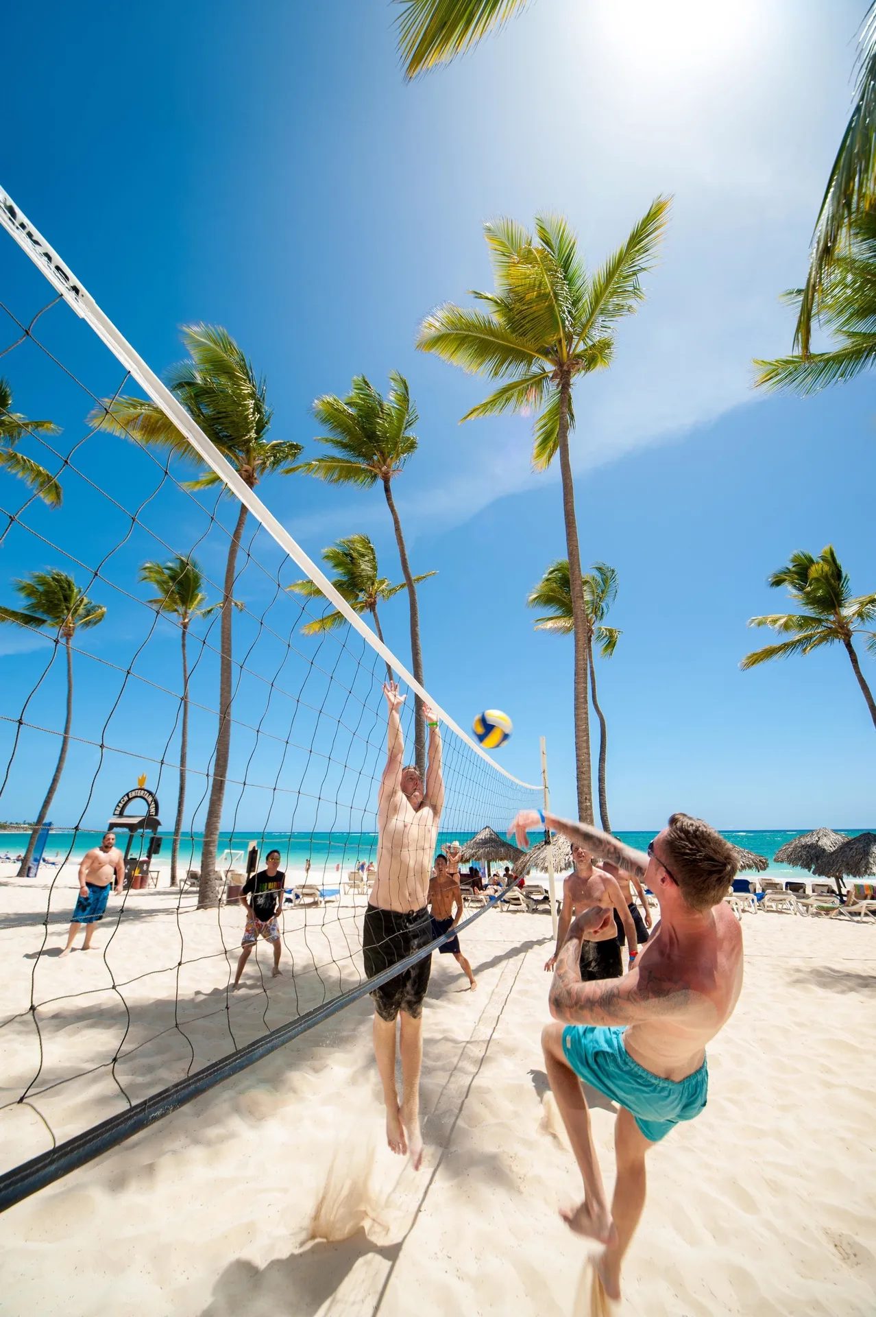 Beach volleyball game on the sand at Princess Family Club Bavaro with palms and turquoise water.